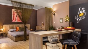 A modern room with a bed, a dining table, chairs, and a wall with a 'Life is Good' sign. - Apartments Kappa (Rijeka)