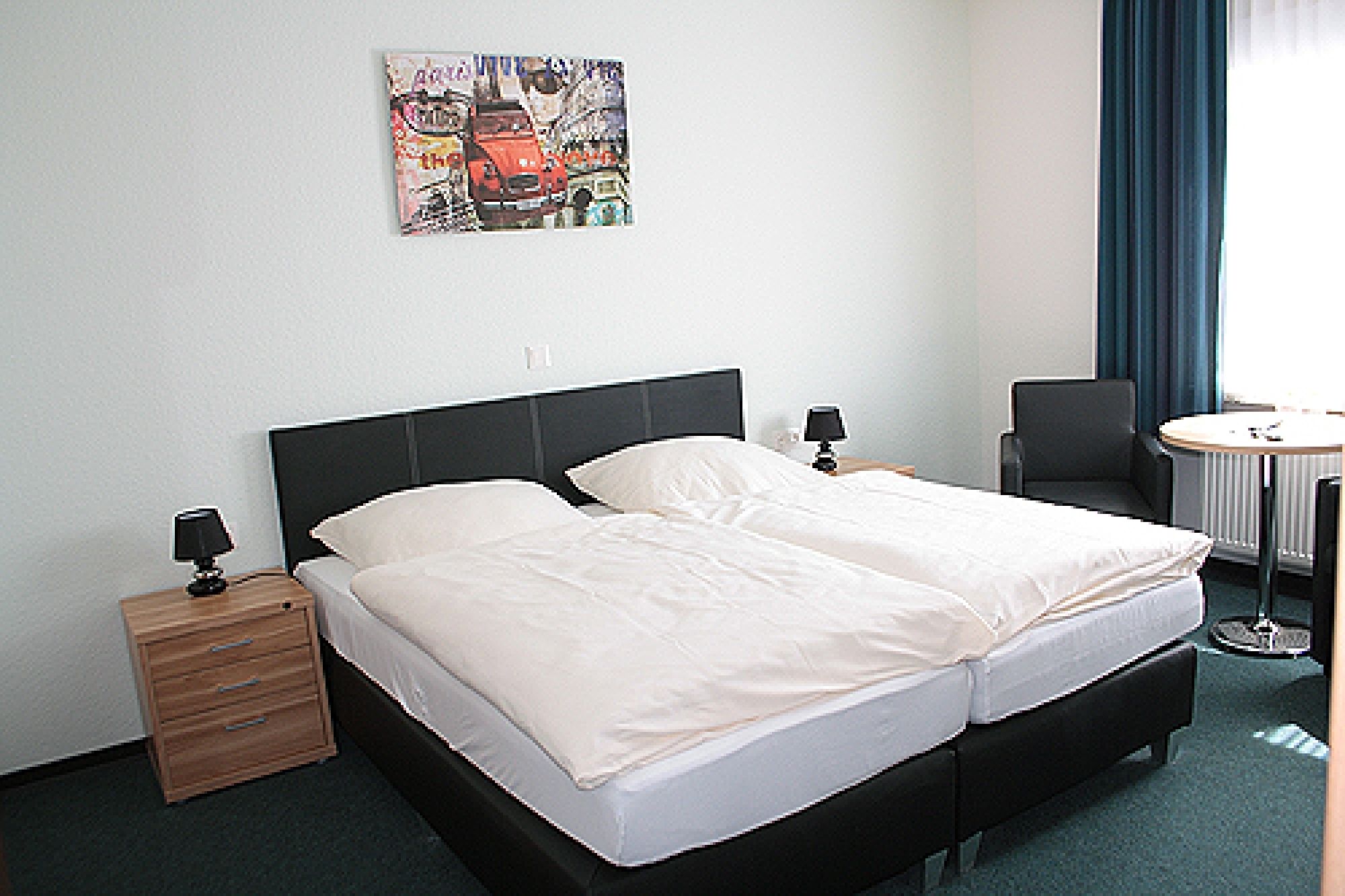 A hotel room with a bed, two bedside tables, a chair, a desk, and a painting on the wall.