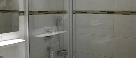 Un baño moderno con ducha de vidrio, lavamanos y espejo.