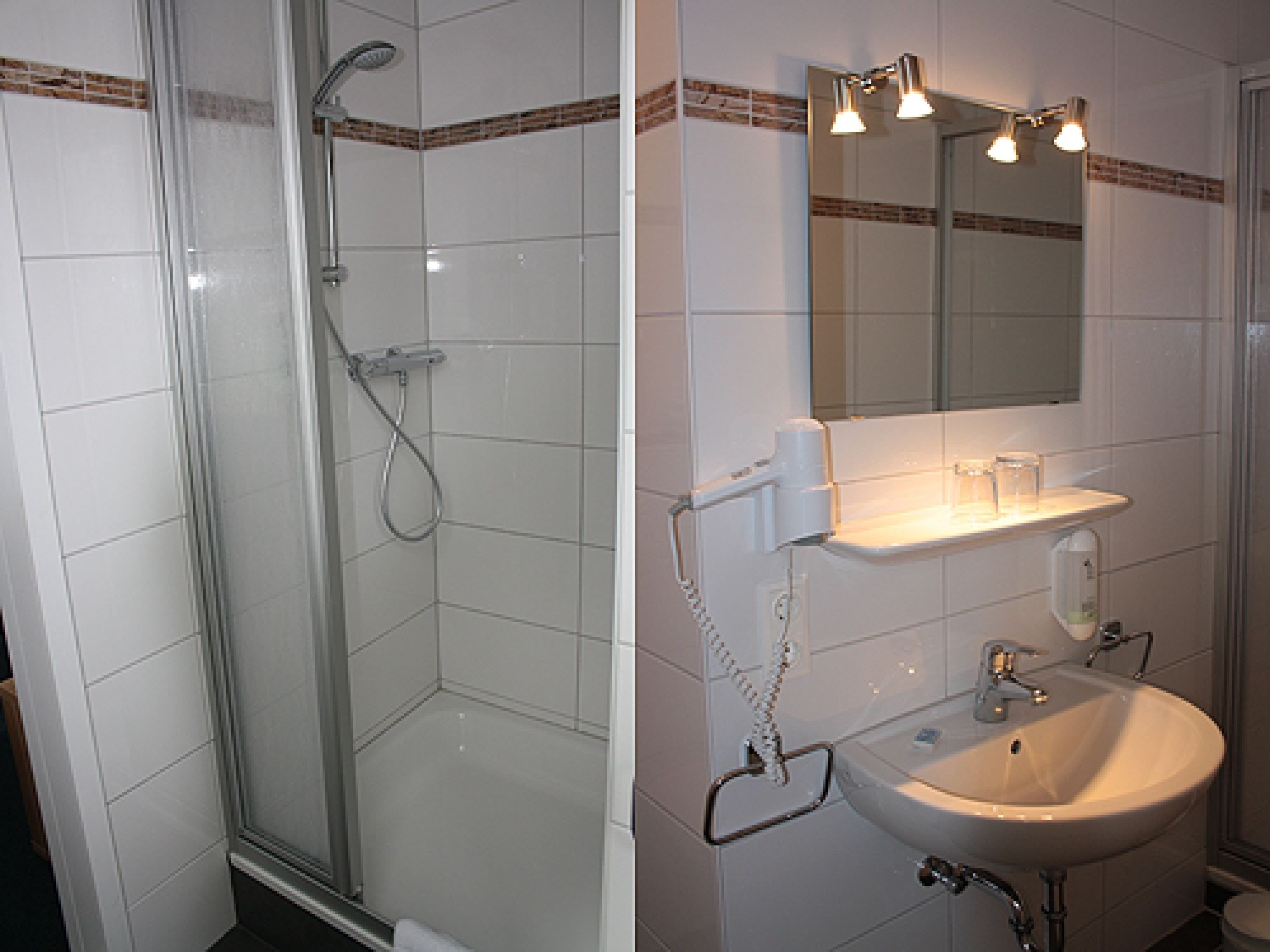A bathroom with a glass-enclosed shower, a sink, and a mirror with lights above it.