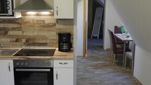 Una cocina compacta con estufa, horno y cafetera, que da paso a un comedor con mesa y sillas.