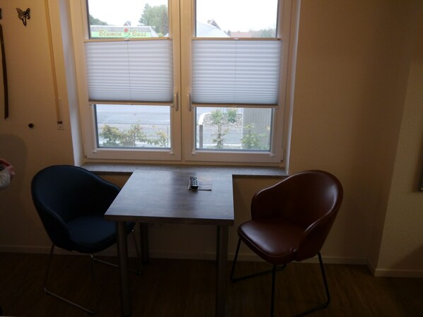 A small room with a window, a table, and two chairs. - Hotel Haus Wittwer (Emden)
