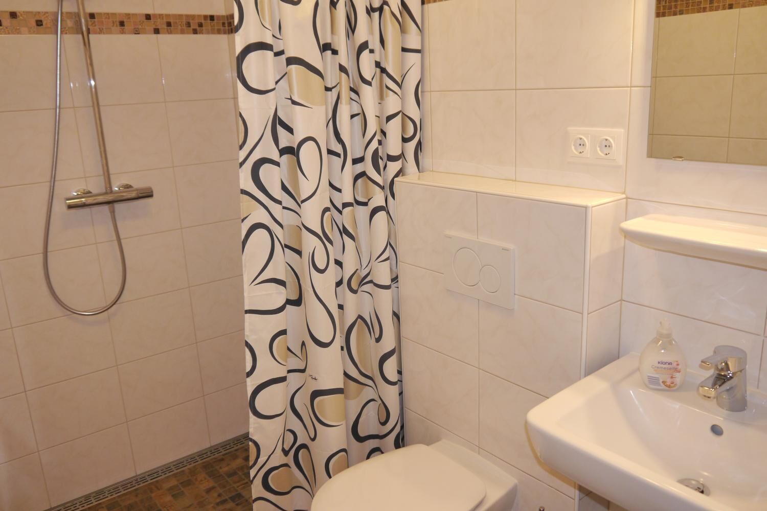 A bathroom with a shower, toilet, and sink.