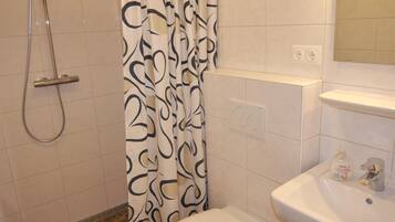 A bathroom with a shower, toilet, and sink.