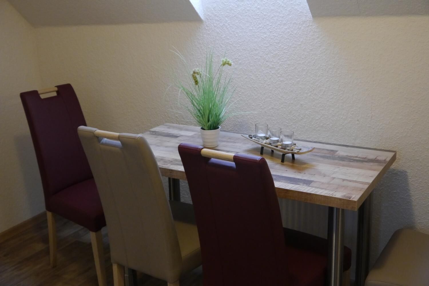 Et spiseområde med et træbord, to stole, en potteplante og et fad med stearinlys.