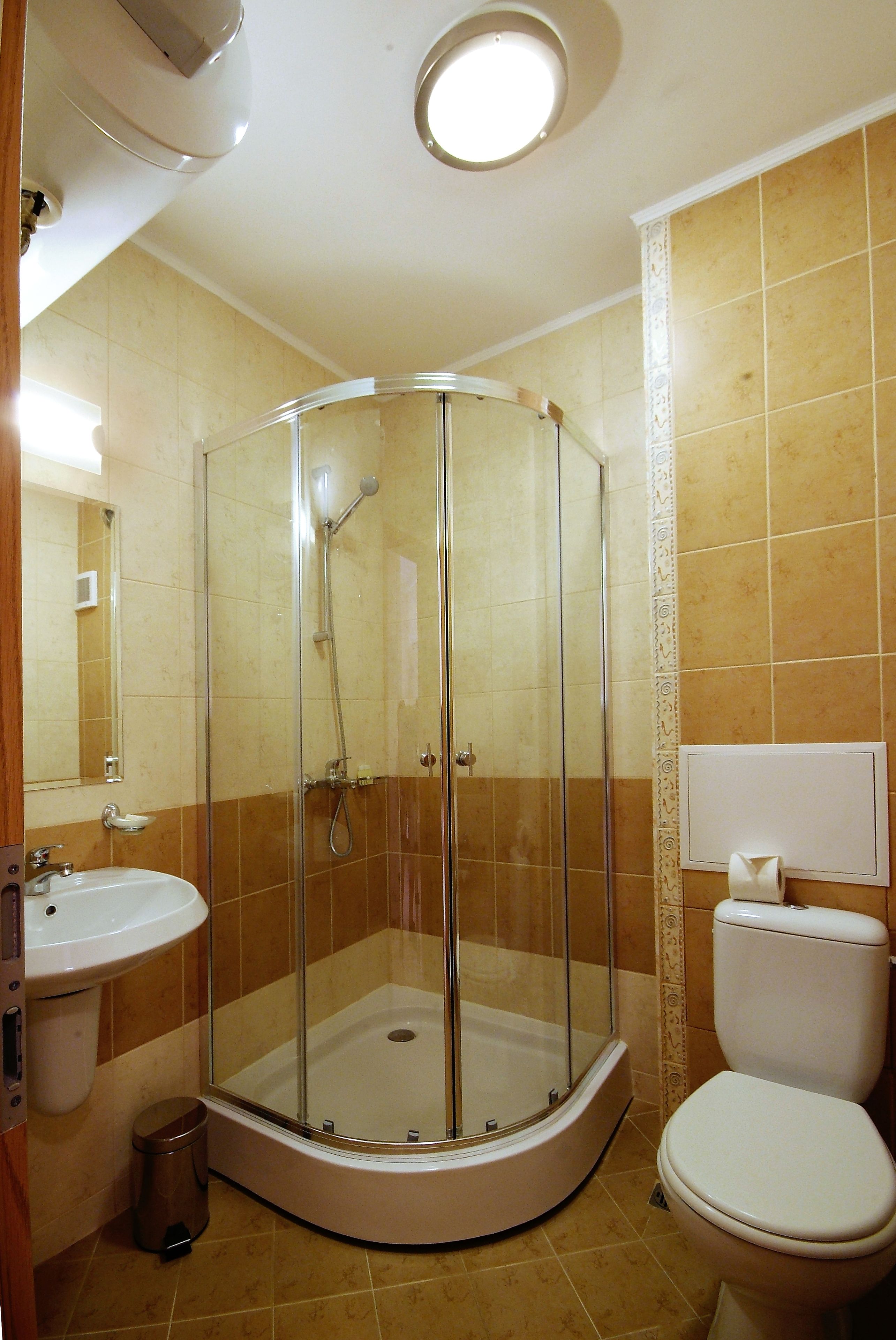 Un baño con ducha de vidrio, lavamanos e inodoro.