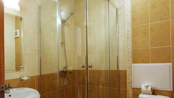 Un baño con ducha de vidrio, lavamanos e inodoro.