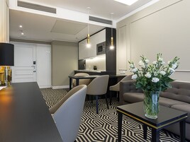 Habitación de hotel moderna con zona de comedor, sofá y un florero.