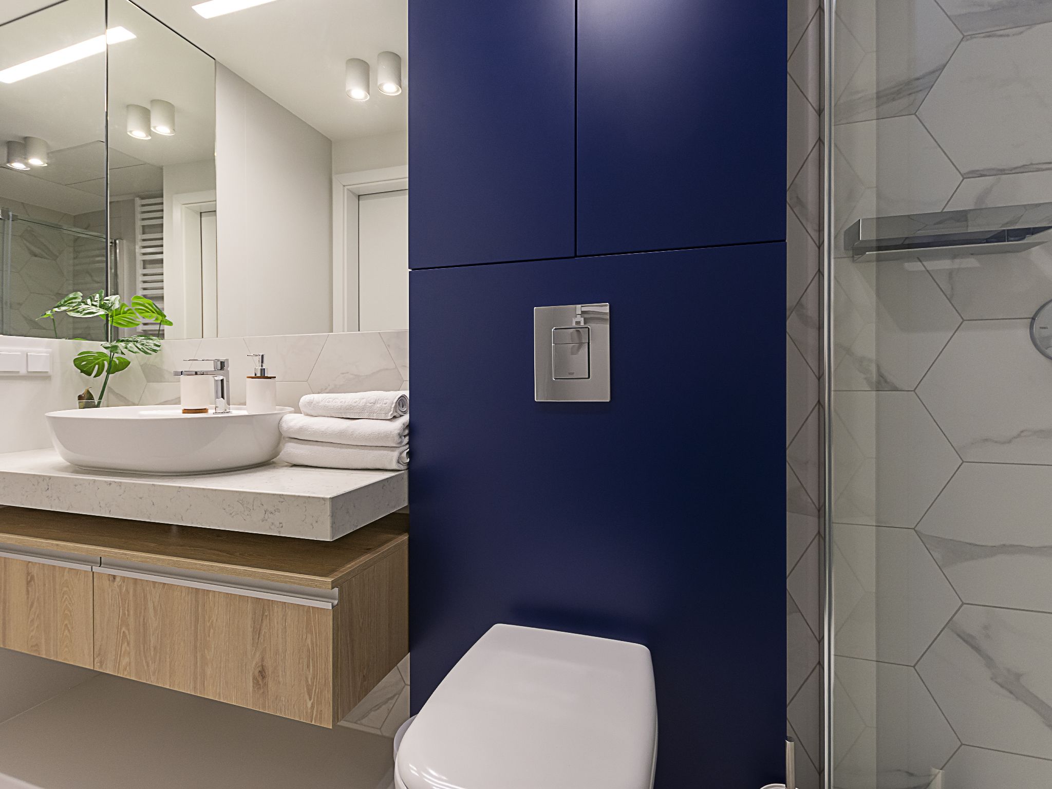 Ein modernes Badezimmer mit Waschbecken, Spiegel, Toilette und einer blauen Wand.