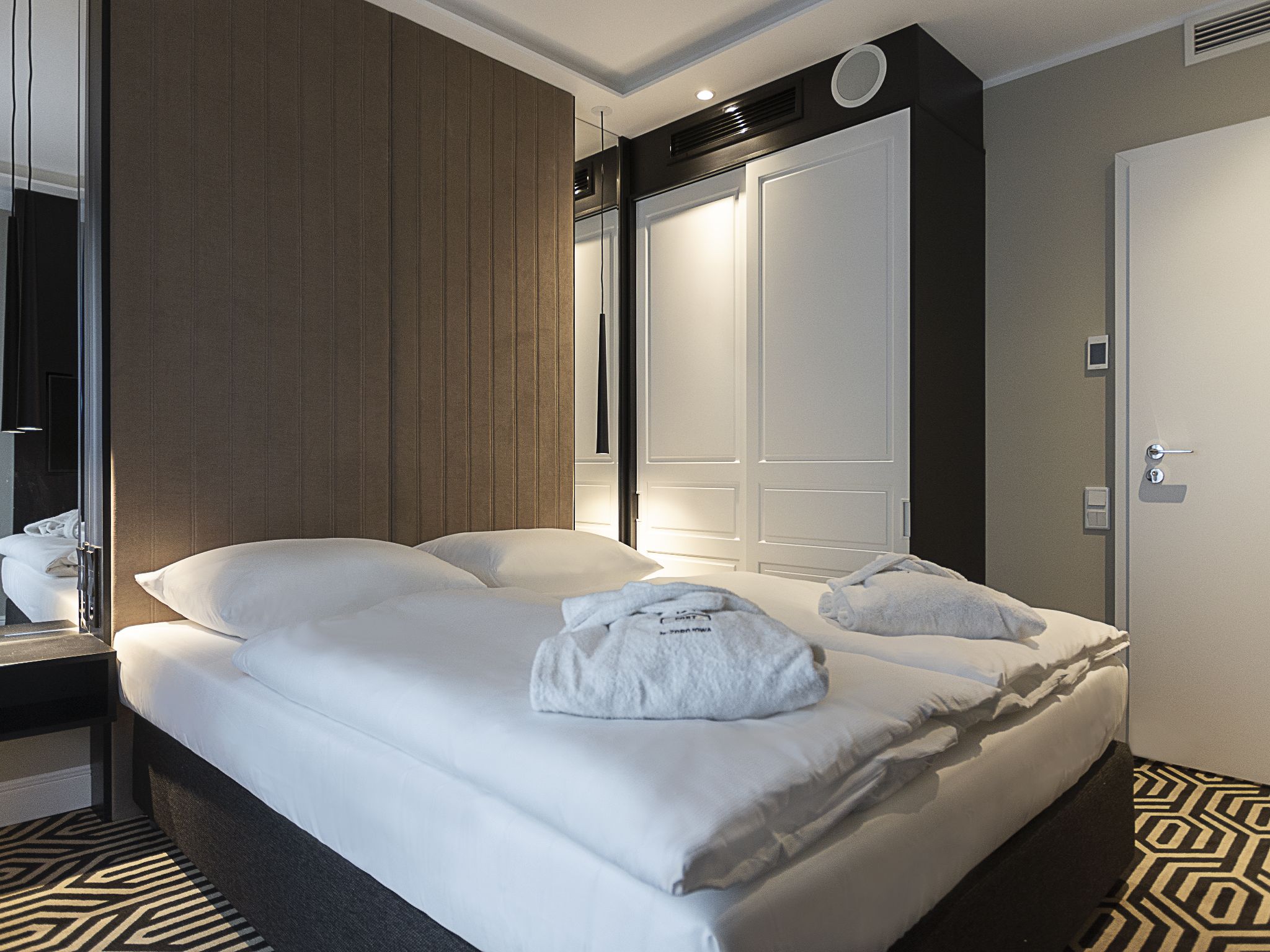 Ein Hotelzimmer mit einem großen Bett, einem Kleiderschrank und einem Spiegel.