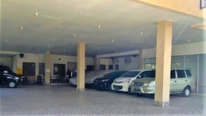 A covered parking area with several cars parked under a roof supported by columns. - Pondok Bintang (Makassar)