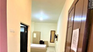 A hotel corridor with a bed, wardrobe, and a door with a notice. - Pondok Bintang (Makassar)
