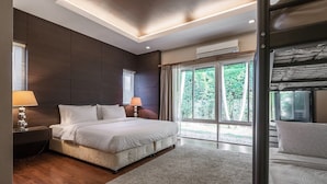 Une chambre moderne avec un grand lit, un plancher en bois et une vue sur la verdure grâce à de grandes fenêtres.