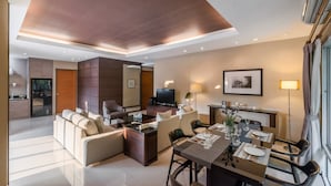 Une chambre d’hôtel moderne dotée d’un espace salon, d’un coin repas et d’une télévision.