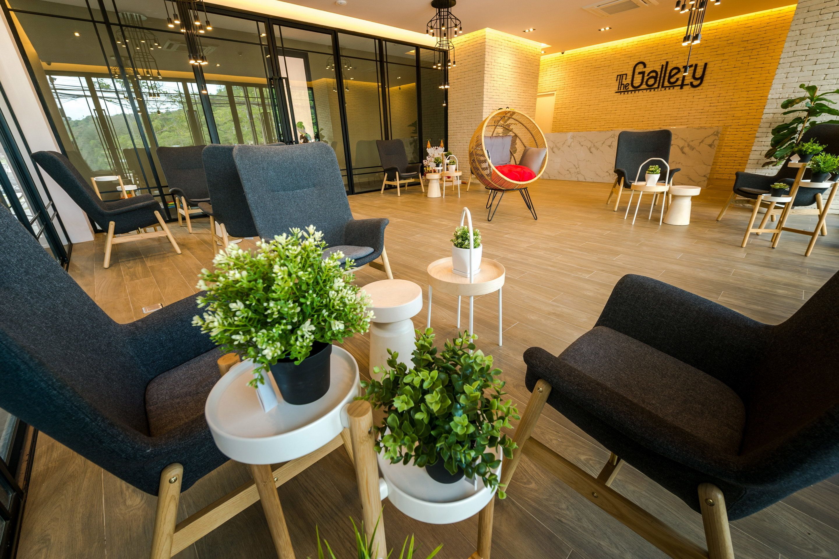 Ett modernt loungeområde med bekväma sittplatser, krukväxter och en väl synlig skylt med texten ”The Gallery”.