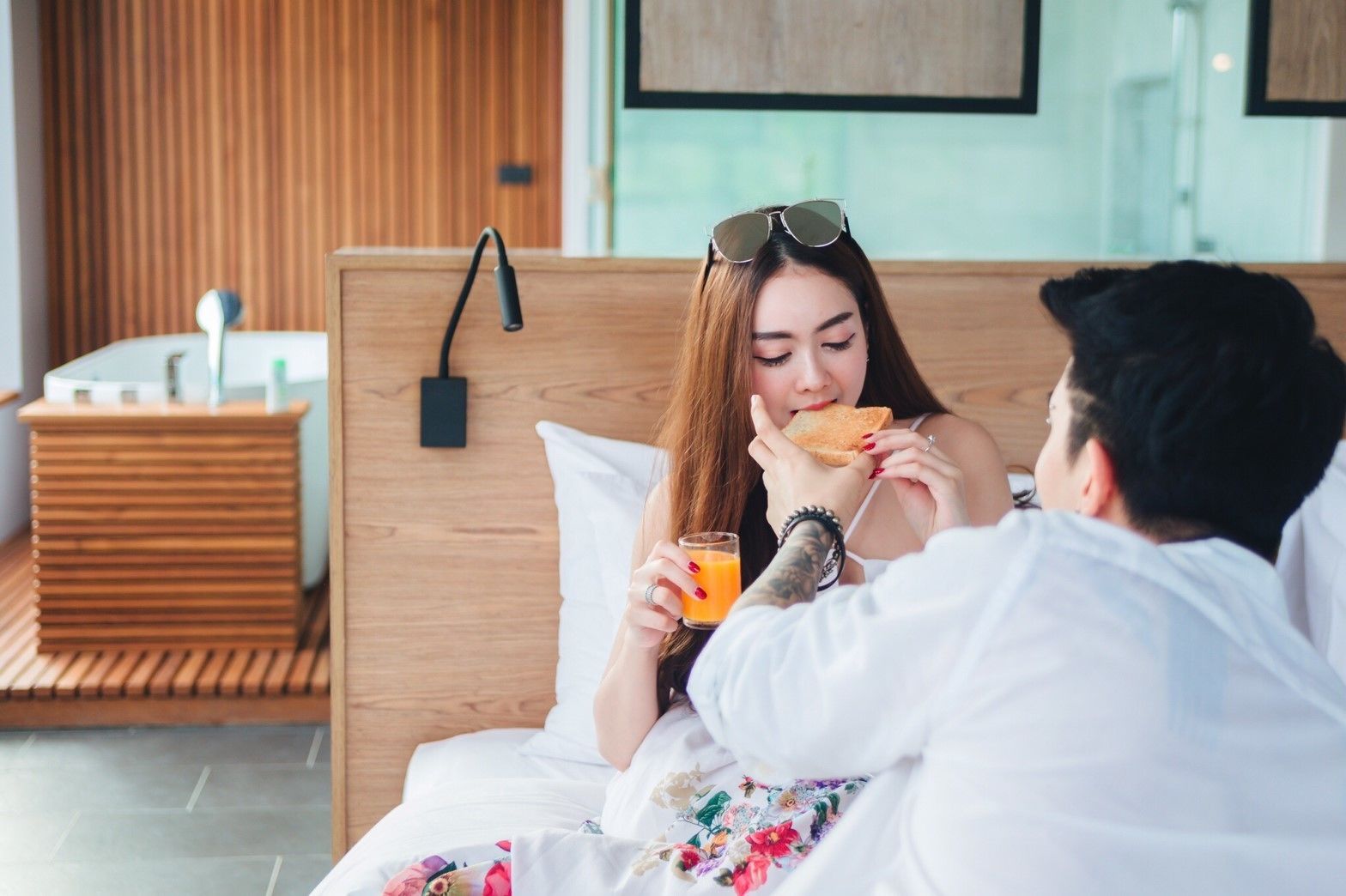 Una habitación de hotel con cabecera de madera, una mesita de noche con lámpara y una cama con colcha estampada.