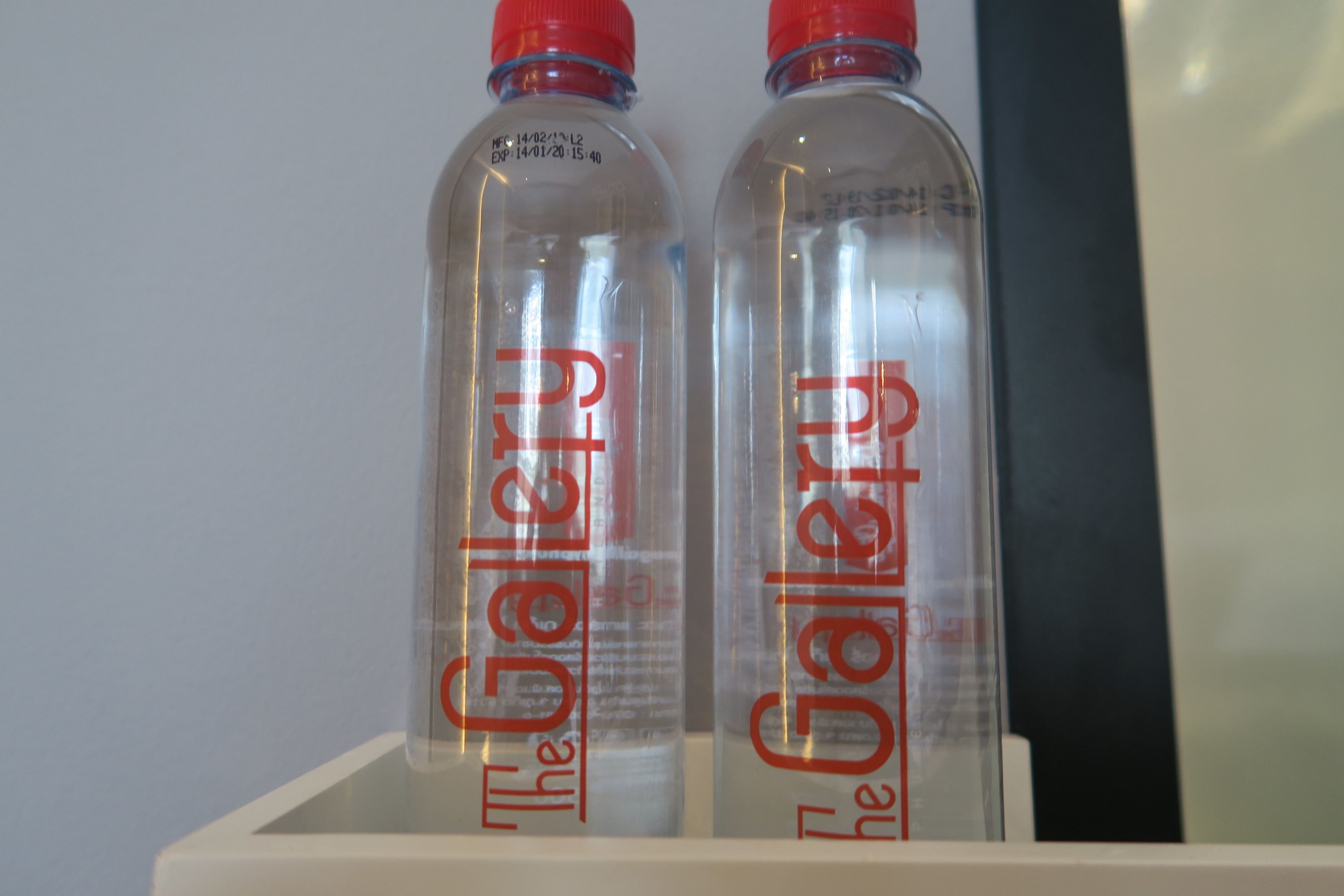 Two clear plastic bottles with red caps and red text on a white shelf.