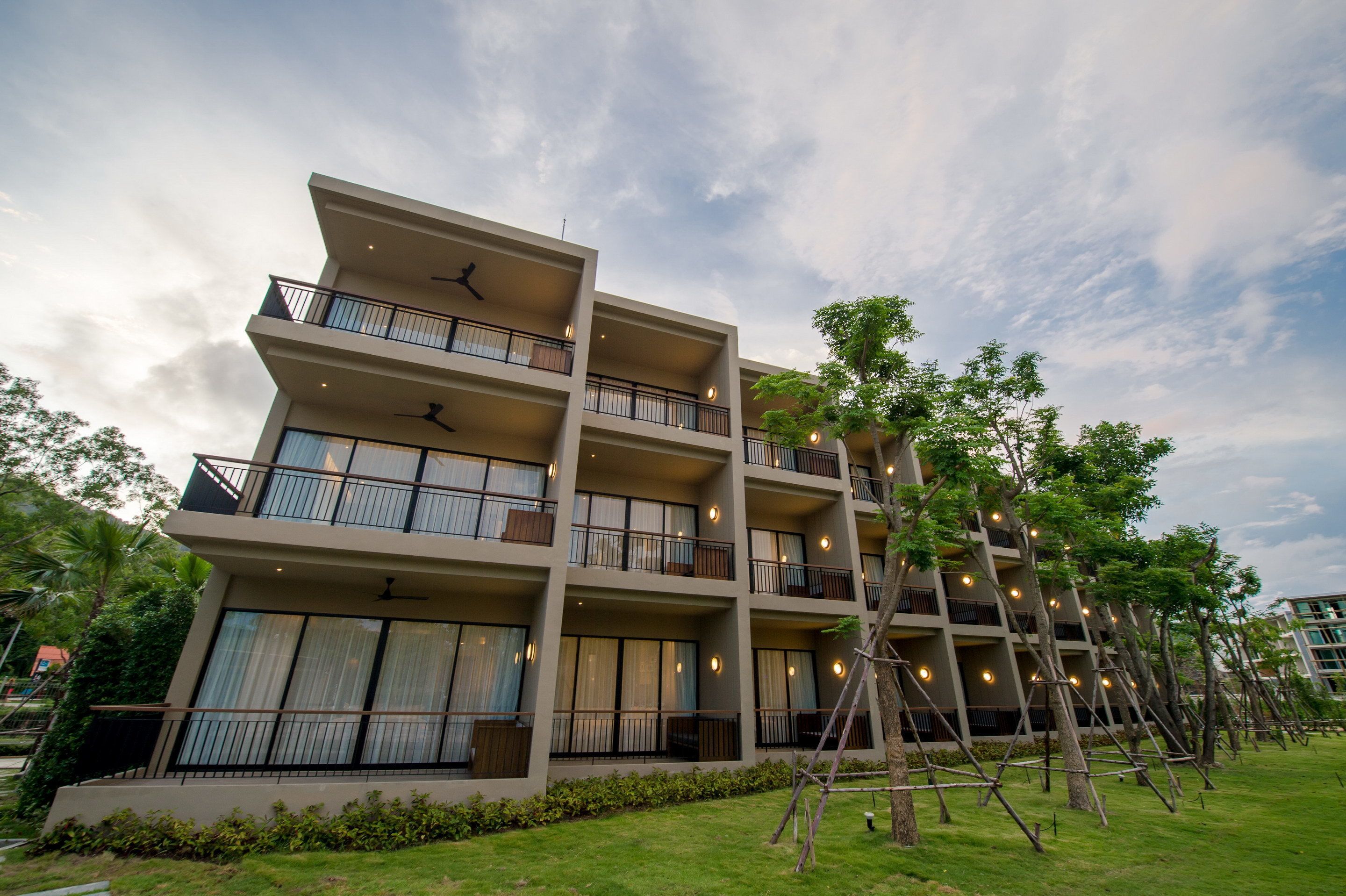 A multi-story hotel with balconies, large windows, and a well-maintained lawn.