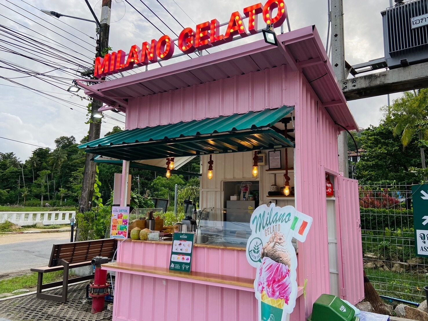 Een roze ijssalon met een bord waarop ‘MILANO GELATO’ staat en een menukaart.