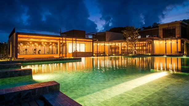 A modern hotel with a swimming pool, glass-walled rooms, and outdoor lighting. - The Gallery Hotel Nai Harn (Rawai)