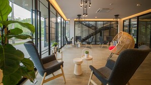 A modern interior with large windows, a staircase, and contemporary furniture. - The Gallery Hotel Nai Harn (Rawai)