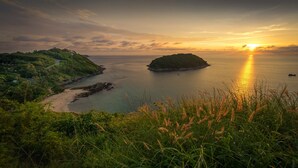 A coastal landscape with a road leading to a beach and a small island. - The Gallery Hotel Nai Harn (Rawai)