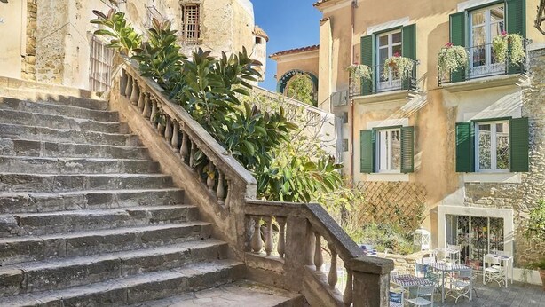 A stone staircase leading to a courtyard with outdoor seating and potted plants. - Palazzo Gentilcore (Castellabate)