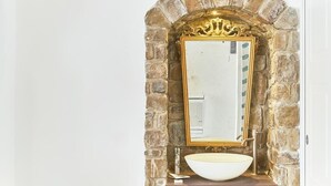 A bathroom with a stone arch, a gold-framed mirror, and a white sink. - Palazzo Gentilcore (Castellabate)