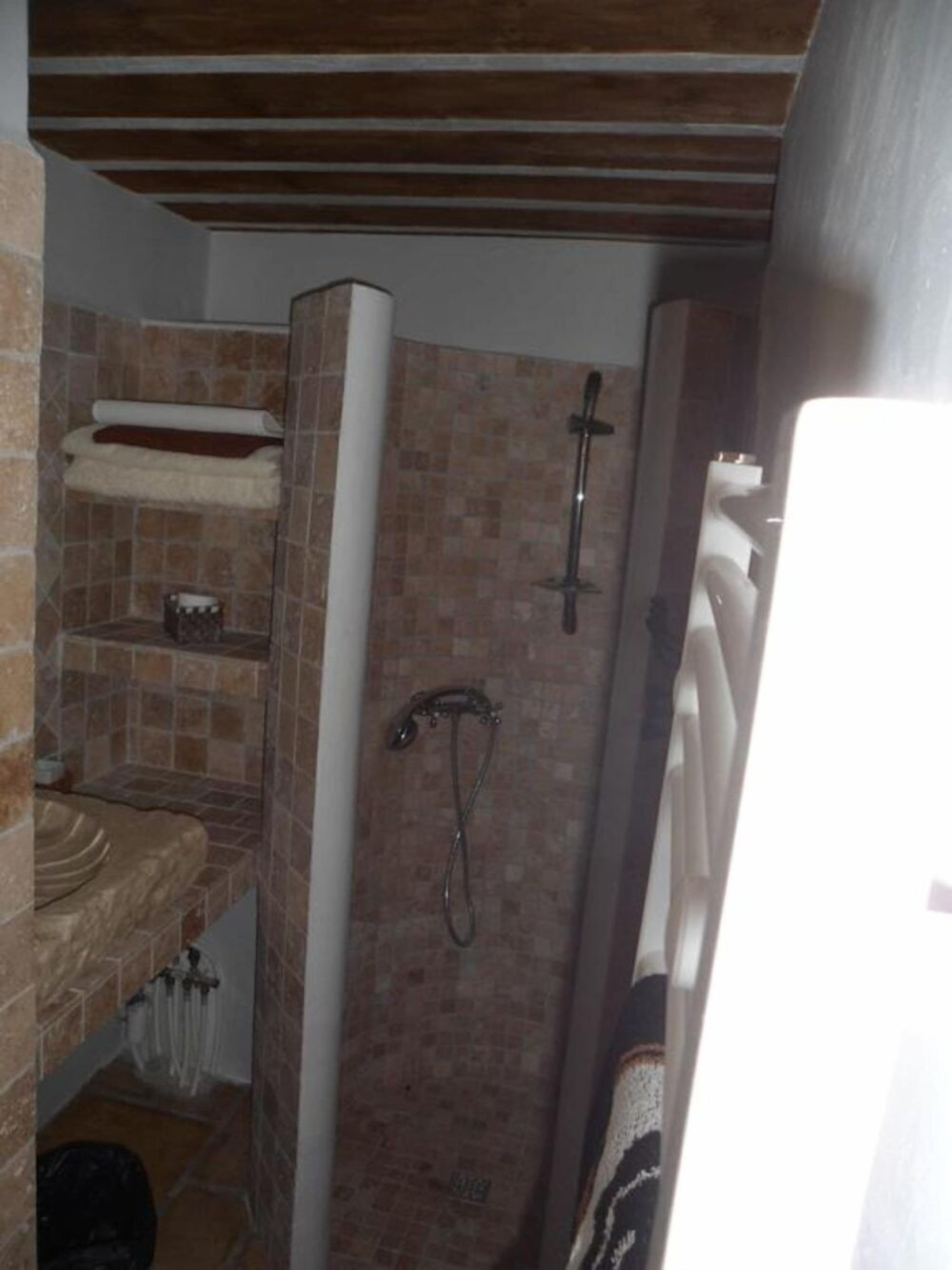 Un bagno con doccia, lavandino e porta asciugamani.