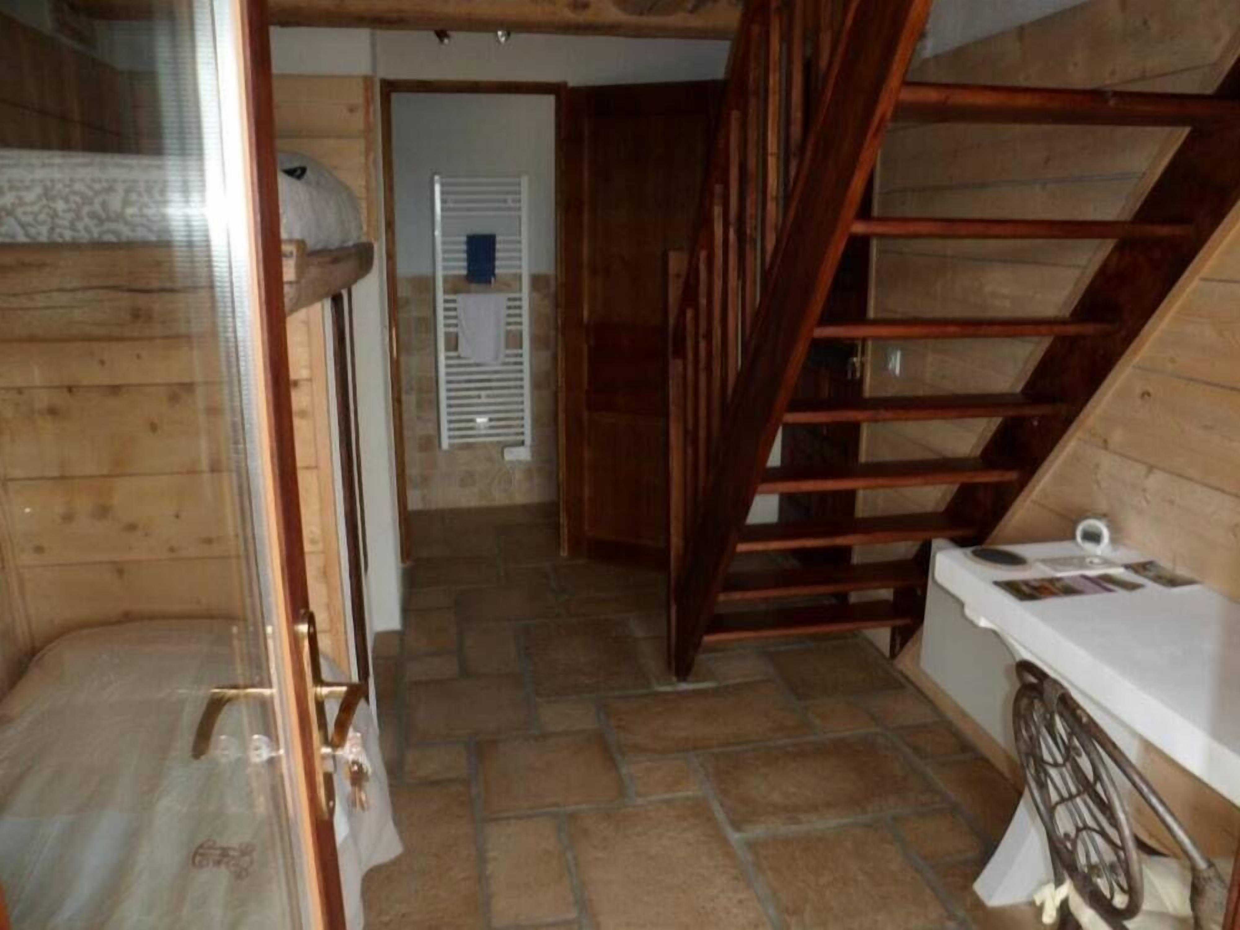 Interior de madera con literas, una escalera y una pequeña mesa con objetos encima.