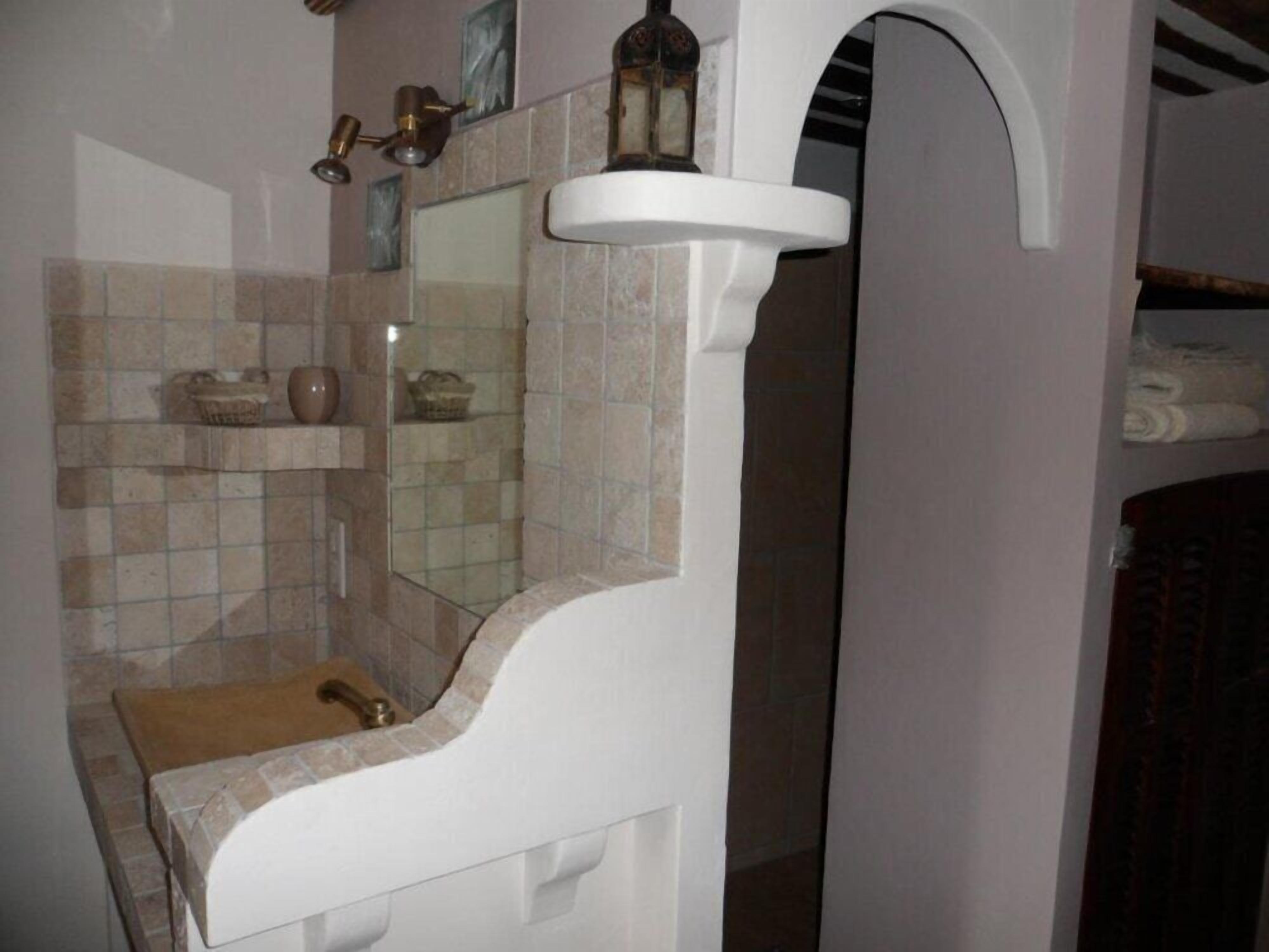 A bathroom with a white sink, a mirror, and a tiled backsplash.