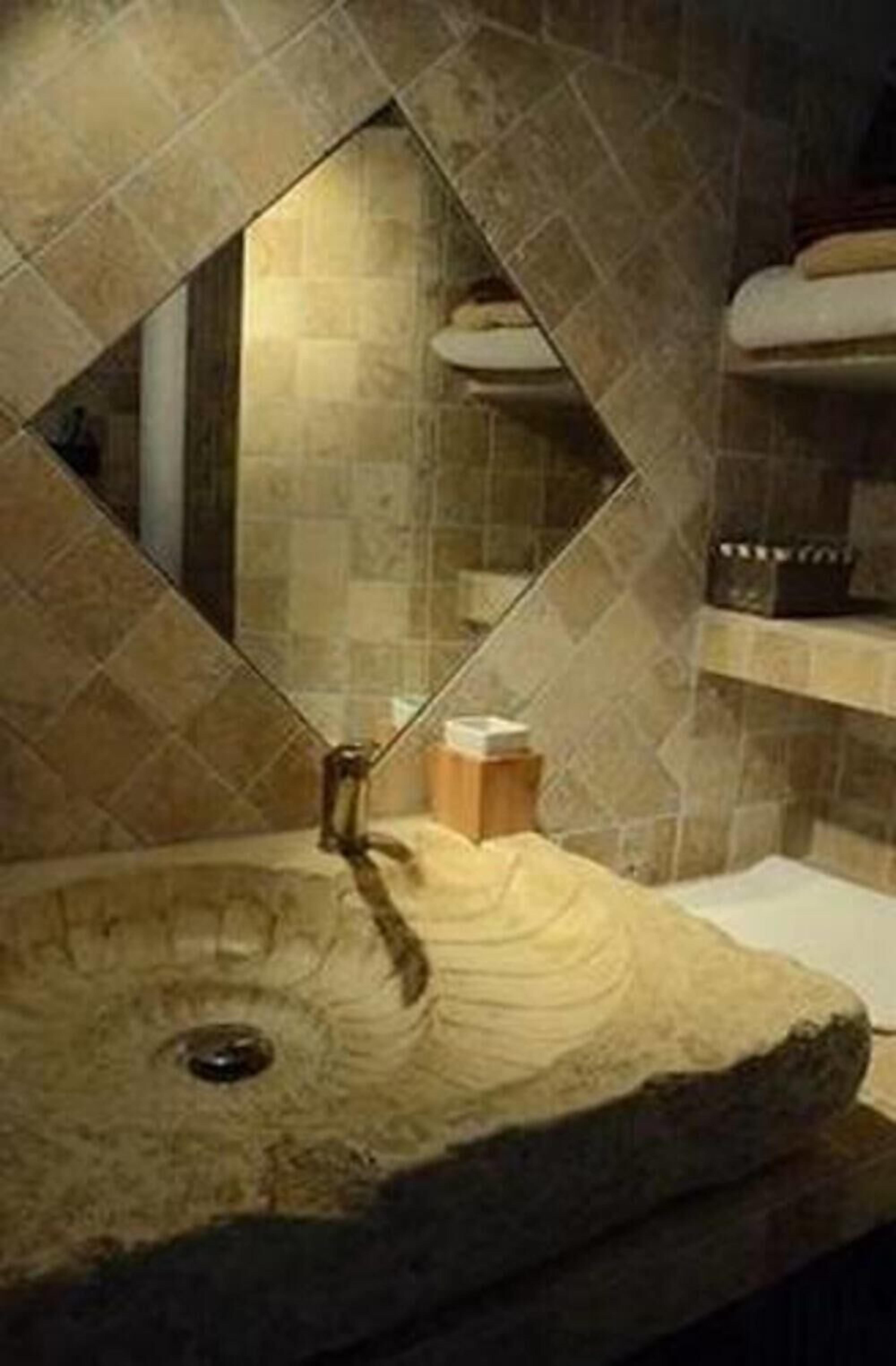 A bathroom with a stone sink, a mirror, and a tiled wall.