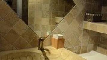 A bathroom with a stone sink, a mirror, and a tiled wall.