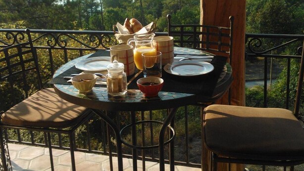 A table set for breakfast with a scenic view of a lake and forest. - Les Gites du Lac - Chambre d'hotes (Montauroux)