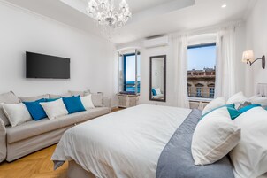 Un hotel moderno con una cama grande, un sofá, un televisor y vista al mar.