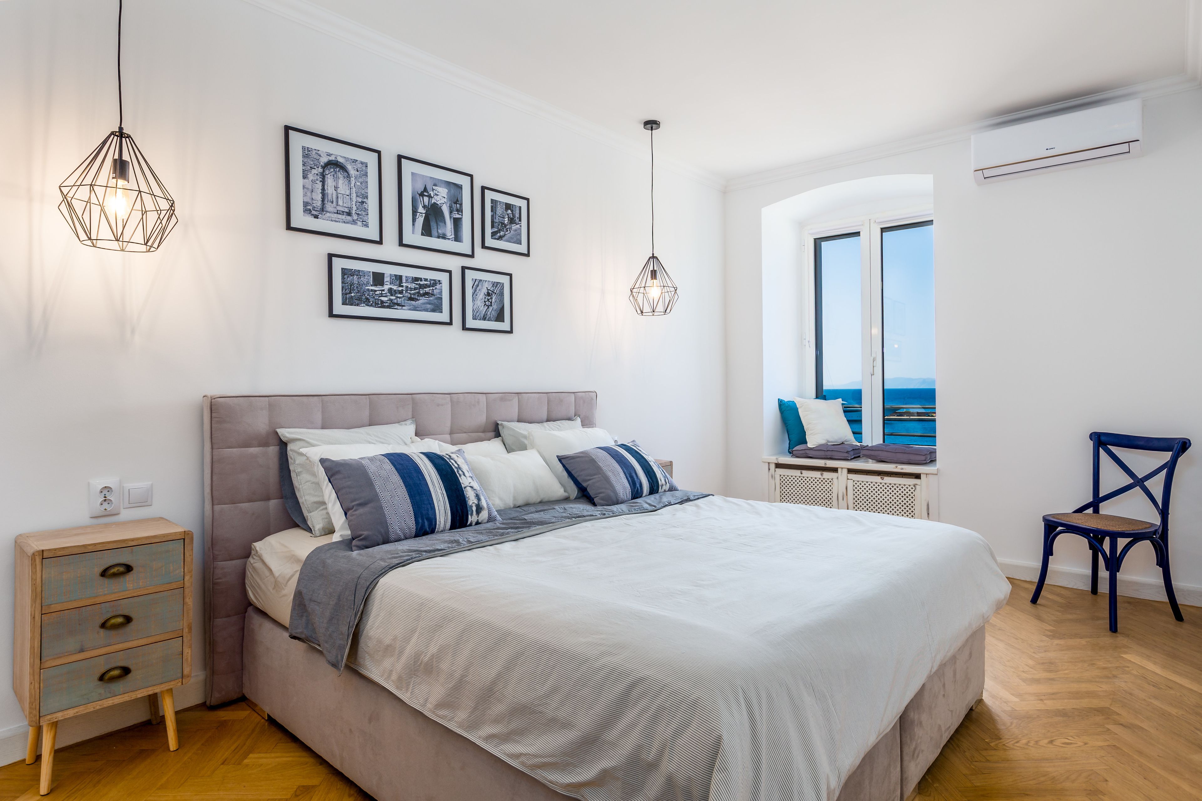 Een slaapkamer met een bed, nachtkastjes, een stoel en een raam met uitzicht.