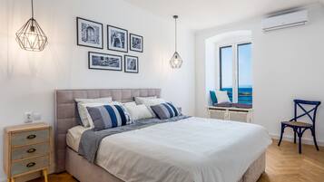 Een slaapkamer met een bed, nachtkastjes, een stoel en een raam met uitzicht.