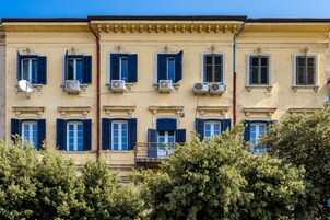 Un edificio con varias ventanas, algunas con contraventanas y unidades de aire acondicionado.