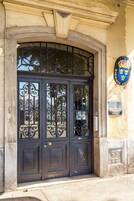 A double door with intricate metalwork and a coat of arms plaque on the wall.