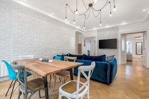 Una sala de estar moderna con una mesa de comedor de madera, sofá azul y paredes de ladrillo blanco.