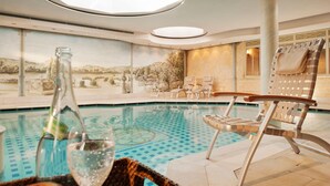 A pool area with lounge chairs, a bottle of champagne, and a glass of water. - Hotel Aarnhoog (Sylt)