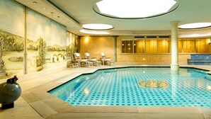 An indoor swimming pool with a tiled floor, a mural on the wall, and several lounge chairs. - Hotel Aarnhoog (Sylt)