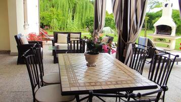 Enjoy al fresco dining in a serene garden setting, surrounded by lush greenery and equipped with a grill for outdoor cooking.