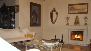 Uma sala de estar com um sofá branco, uma mesa de centro com um livro, lareira e decorações na parede.