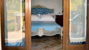 Quarto com cama, lustre e vista pela janela.