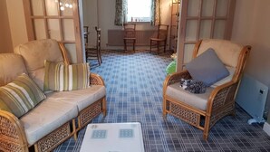 A room with two wicker sofas, a small table, and a cat. - House - Sleeps 4 - Pets Ok - Parking - Garden (Guisborough)