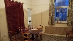 A dining area with a table and chairs, a red curtain, and a window with patterned curtains. - House - Sleeps 4 - Pets Ok - Parking - Garden (Guisborough)