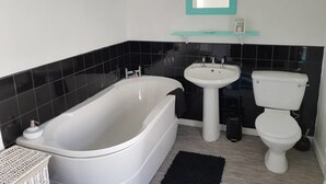A modern bathroom with a freestanding bathtub, a pedestal sink, and a toilet. - House - Sleeps 4 - Pets Ok - Parking - Garden (Guisborough)
