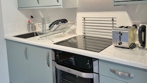 Eine moderne Küche mit hellblauen Schränken, einer Edelstahl-Dunstabzugshaube, einem Einbauofen und einem Toaster.