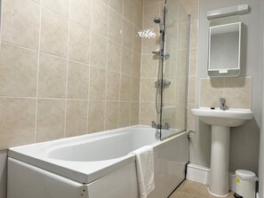 A bathroom with a bathtub, a glass-enclosed shower, a sink, and a mirror. - Warehouse Apartments (Ulverston)